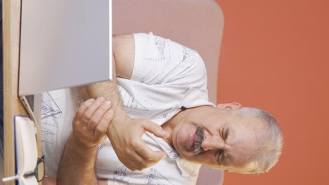 Vertical-video-of-The-wrist-of-the-old-man-using-a-laptop-hurts.